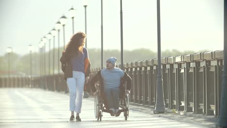 Hombre-discapacitado-en-silla-de-ruedas-caminar-juntos-a-su-novia-en-el-muelle