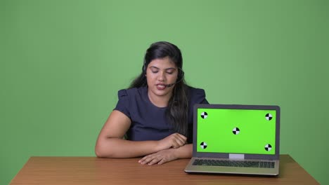 Young-overweight-beautiful-Indian-businesswoman-against-green-background