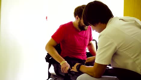 Doctor-putting-the-robotic-exoskeleton-for-disabled-man