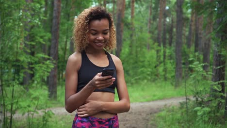 joven-hermosa-mujer-afro-americana-con-el-cabello-rizado-está-chateando-en-su-teléfono-antes-de-correr