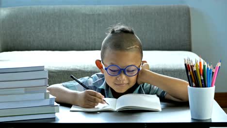 Boy-with-disability,-brain-disorders-And-Left-eye-is-not-visible-from-brain-surgery.-He-is-thinking-and-write-into-book,-Happy-smile-at-home.-education-concept