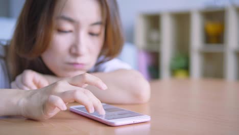 Asian-woman-using-cellphone-in-living-room