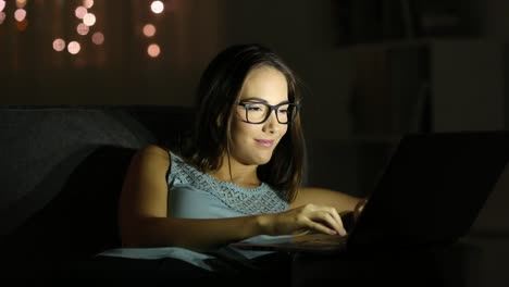 Mujer-con-anteojos-usando-una-laptop-en-la-noche