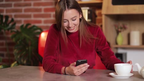 Mujer-joven-navegando-por-internet,-revisar-novedades-en-redes-sociales-durante-el-uso-de-smartphone-en-la-cocina.