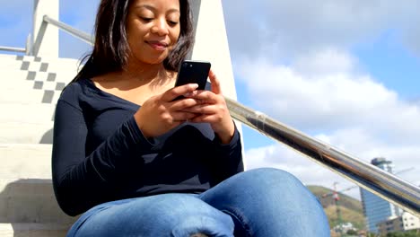 Beautiful-woman-using-mobile-phone-on-stairs-4k