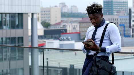 Dark-skinned-businessman-text-messaging-outdoors