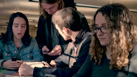 Four-teenagers-or-young-adults-using-their-mobile-phones-inside-a-public-place