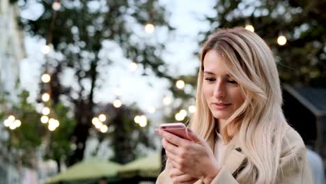 Beautiful-woman-using-smart-phone-technology-app-walking-through-city-streets.-Girl-scrolls-through-social-media-on-device,-reading-news-on-app.