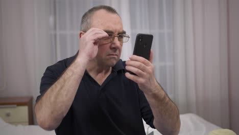 an-elderly-man-with-glasses-is-trying-to-see-something-in-the-phone