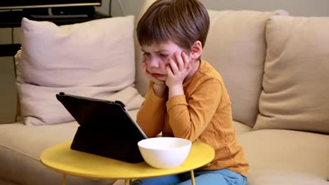 Niño-usando-Tablet-PC-en-la-cama-en-casa.-Niño-lindo-en-el-sofá-está-viendo-dibujos-animados,-jugando-juegos-y-aprendiendo-desde-el-ordenador-portátil.-Educación,-diversión,-ocio,-felicidad,-tecnología-informática-moderna-y-comunicación.