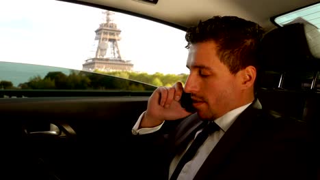 Un-joven-atractivo-en-un-traje-está-sentado-en-el-coche-junto-a-la-Torre-Eiffel