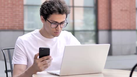 Young-Man-Using-Smartphone-and-Laptop-Outdoor