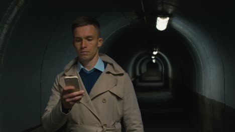 Serious-man-with-mobile-phone-going-through-the-tunnel