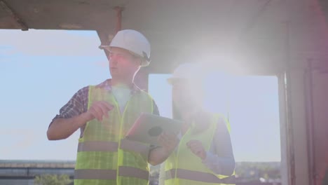 Supervisor-of-a-building-under-construction-man-discussing-with-engineer-designer-woman-the-progress-of-construction-and-examines-a-building-plan