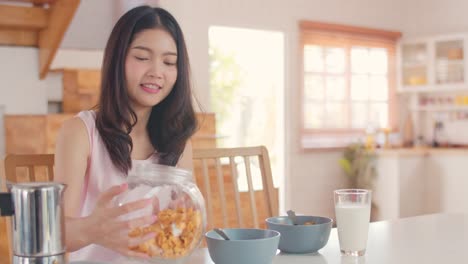 Asian-Lesbian-couple-using-mobile-phone-talk-with-friend-while-have-breakfast-in-kitchen-in-the-morning.