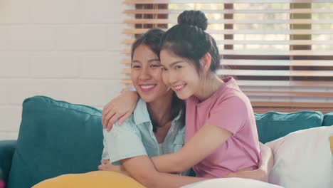 Young-Asian-Lesbian-couple-hug-and-kiss-lying-sofa-in-living-room-at-home.