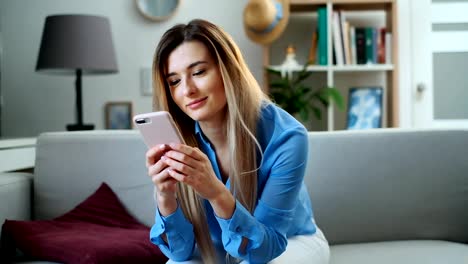 Cerca-de-retrato-de-la-chica-usando-el-dispositivo-móvil-navegando-por-Internet,-manteniéndose-conectado-en-casa-disfrutando-de-un-estilo-de-vida-moderno.-Bonita-mujer-joven-usando-el-teléfono-inteligente-en-el-sofá,-enviando-mensajes-de-texto-mientras