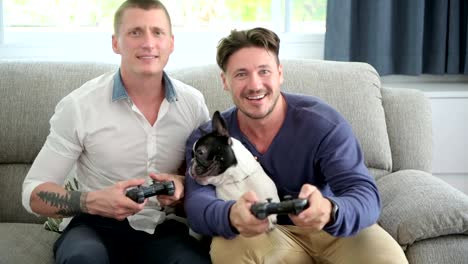 Gay-couple-relaxing-on-couch-with-dog-playing-games.-Very-exciting-mood.