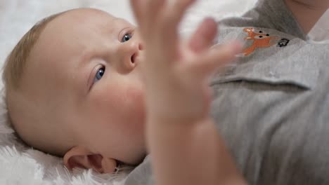 Cute-baby-holds-phone-in-hands.-The-child-plays-with-cell-phone,-examines-it,-tugs-in-his-hands-and-tries-to-eat-smartphone-putting-it-in-his-mouth