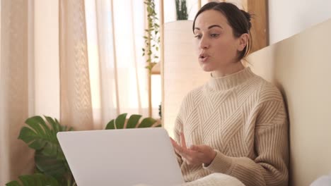 Young-woman-at-home-in-bed-using-laptop-for-video-call