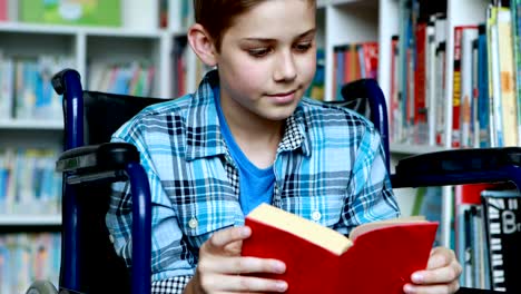 Escolar-discapacitado-en-silla-de-ruedas-libro-de-lectura-en-la-biblioteca