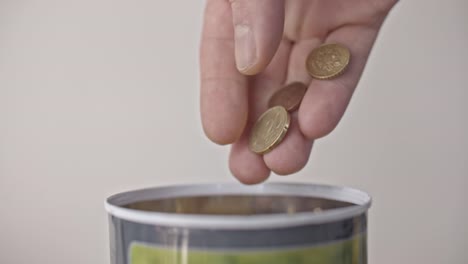 Male-hand-pours-euro-coins-into-a-jar