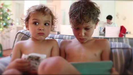 Children-seated-in-living-room-sofa-looking-at-content-online-on-tablet