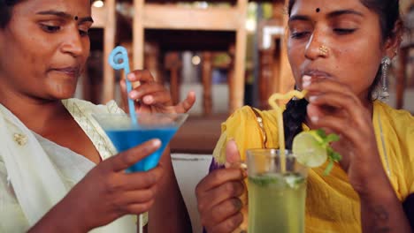 Two-women-chilling-sipping-drinks-using-technology-in-cafe