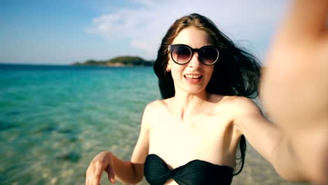 Young-happy-woman-chatting-with-friends-through-internet-using-smartphone-in-ocean-beach