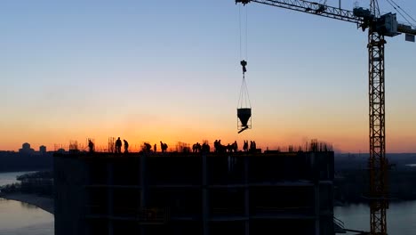 Aerial-shot-of-construction-site-with-cranes-and-workers-at-sunset