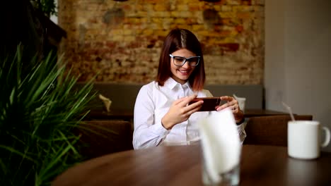 Charmante-Frau-mit-schönen-Lächeln-gute-Nachrichten-auf-dem-Handy-zu-lesen,-während-der-Rest-in-Coffee-Shop,-glücklich-kaukasischen-Frauen-beobachten-ihr-Foto-auf-Zelle-Telefon-und-entspannen-Sie-im-Café-in-der-Freizeit