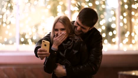 Young-happy-couple-take-selfie-photos-at-camera-on-smart-mobile-cell-phone