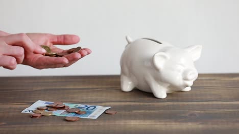 Finance-saving-concept.-Money-throwing-in-the-piggy-bank-euro-coins