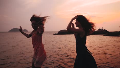 Danza-de-dos-niñas-felices-en-la-playa-al-atardecer-en-cámara-lenta