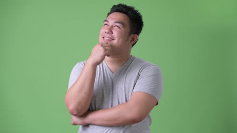 Young-handsome-overweight-Asian-man-against-green-background