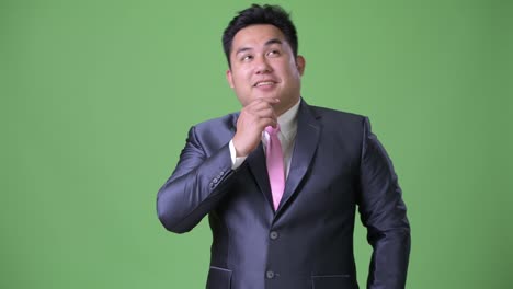 Young-handsome-overweight-Asian-businessman-against-green-background