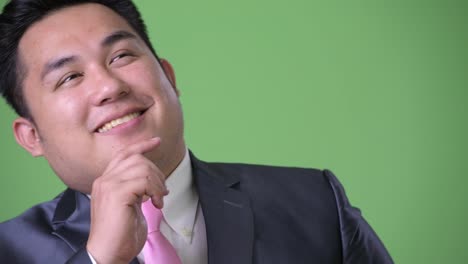 Young-handsome-overweight-Asian-businessman-against-green-background