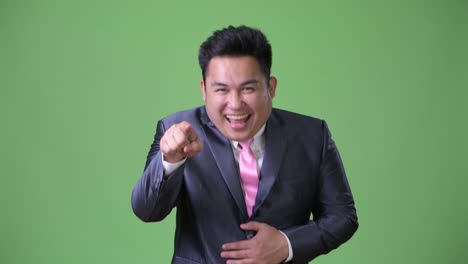 Young-handsome-overweight-Asian-businessman-against-green-background