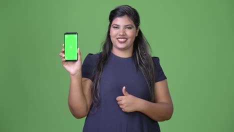 Young-overweight-beautiful-Indian-businesswoman-against-green-background