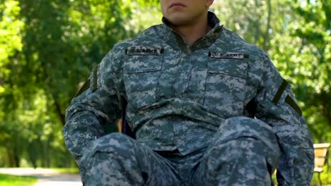 Man-in-military-uniform-sitting-in-wheelchair,-resting-enjoying-nature-in-park