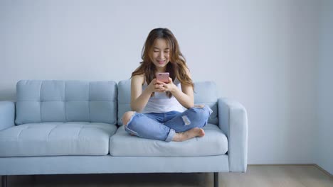 Asiática-mujer-con-celular-en-la-sala-de-estar