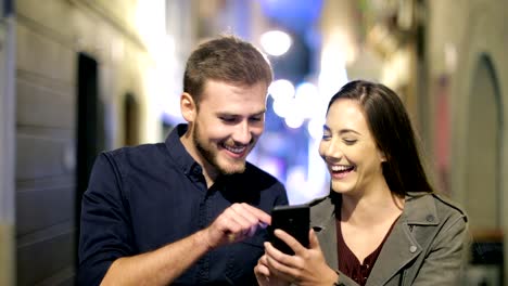 Pareja-feliz-navegación-teléfono-caminando-en-la-noche