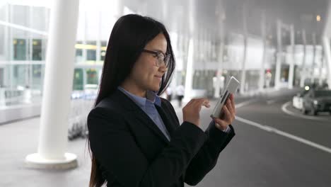 Mujer-bonita-joven-navegando-por-internet-con-tableta-digital-en-edificio-público