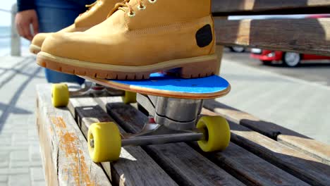 Close-up-of-man-sitting-on-skateboard-near-beach-4k