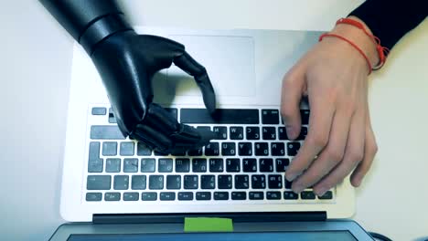 Prosthetic-and-a-healthy-hand-typing-on-the-keyboard.-Futuristic-human-cyborg-concept.