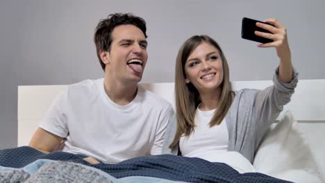 Pareja-feliz-en-la-cama-tomando-Selfie-con-Smartphone,-fotografía