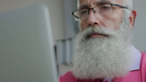 Senior-bearded-man-uses-laptop--in-cafe