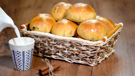 Ostern-Hot-Cross-Buns-in-einem-Korb.-Gießen-Sie-Milch-in-eine-Tasse.