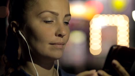 Porträt-der-jungen-schönen-kaukasischen-Frau-mit-Smart-Phone-Hand-halten-im-Freien-in-der-Stadtnacht,-lächelnd,-Gesicht-beleuchteten-Bildschirmlicht-soziales-Netzwerk,-Technologie,-Kommunikation-Konzept