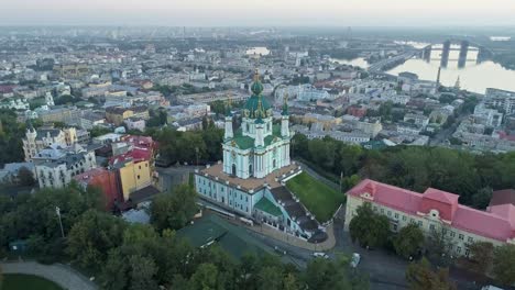 Aerial-view-of-St.-Andrew's-Church-and-the-Podil-District-at-the-Dnieper-River-before-sunset-in-Kyiv,-Ukraine.-4K,-UHD